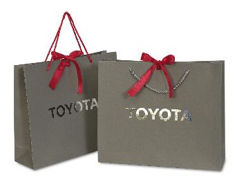 ถุงกระดาษสีเทาเข้มของ Toyota โดดเด่นด้วยโลโก้ 
ปั้มฟอยล์สีเงินที่หน้าถุง
