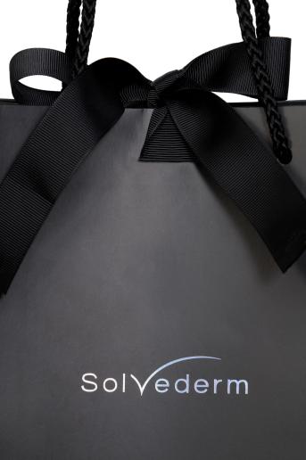 ถุงกระดาษสีดำสวย พิมพ์ชื่อ Solvederm ปั๊มฟอยล์สีรุ้งข้างถุง