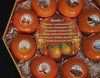 ส้มสีทองผลไม้มงคล 8 ผล ส่งต่อโชคลาภ 8 ประการพิมพ์บนสติกเกอร์วงกลมแปะติดไว้กับผลส้ม  